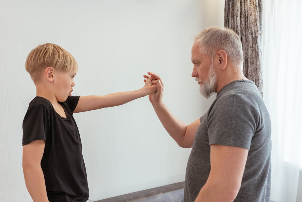 A grandfather and his grandson practicing exercises together indoors.