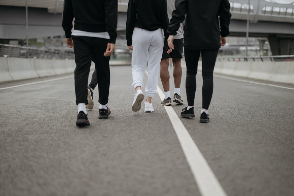 Back view of a group walking on an urban road in casual activewear, highlighting urban fitness culture.
